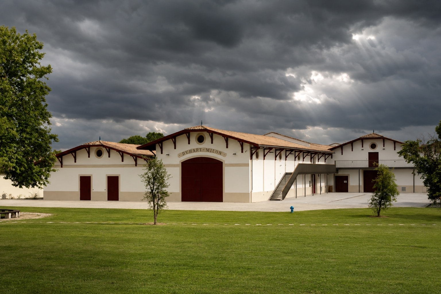 Château Duhart-Milon winery beneath storm clouds and sunbeams in Pauillac, Bordeaux